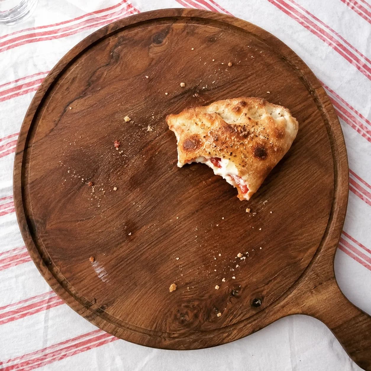 Calzone dorado con una mordida, relleno de muzzarella y tomate a la vista
