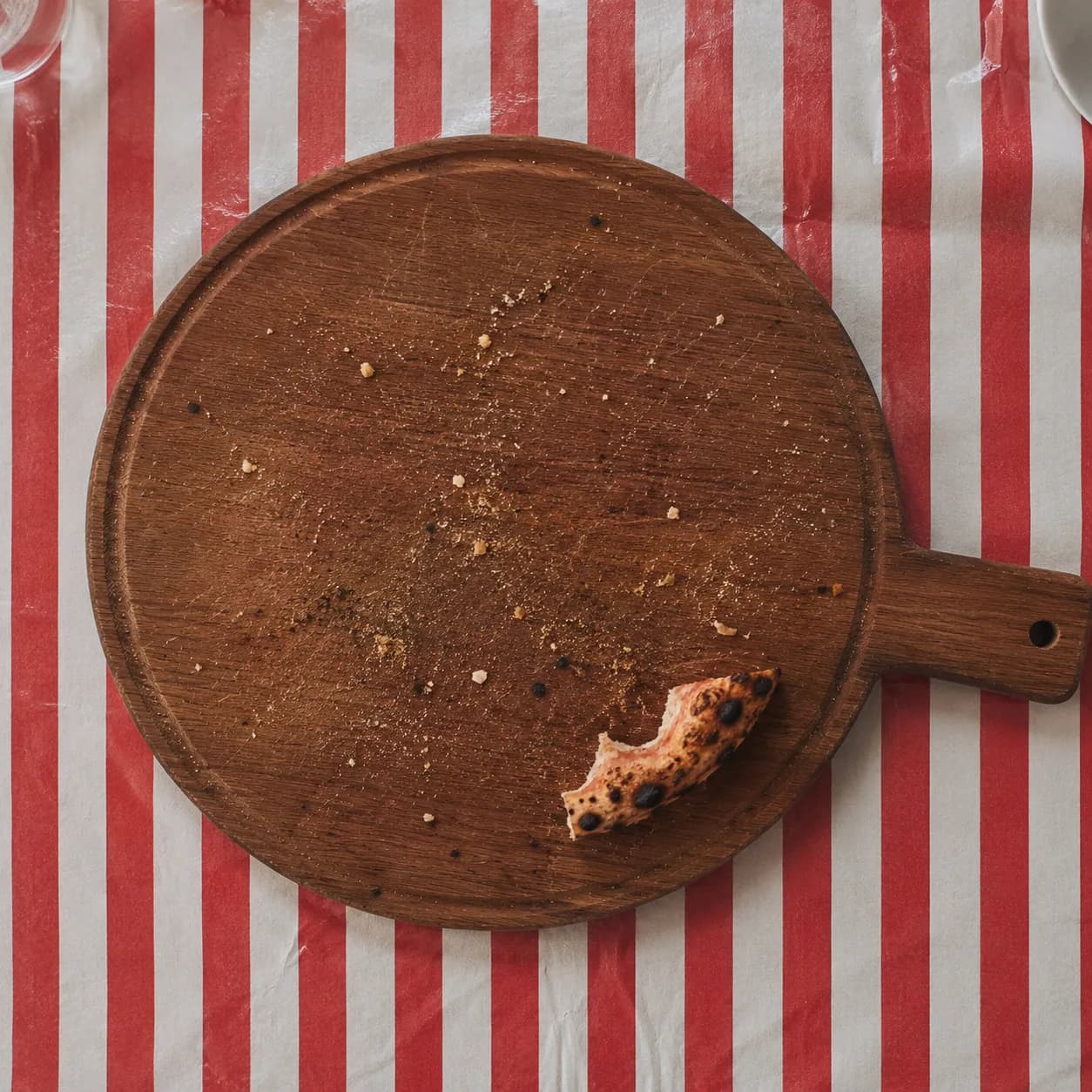 Tabla de pizza vacía: solo quedan las migas y un cachito de borde